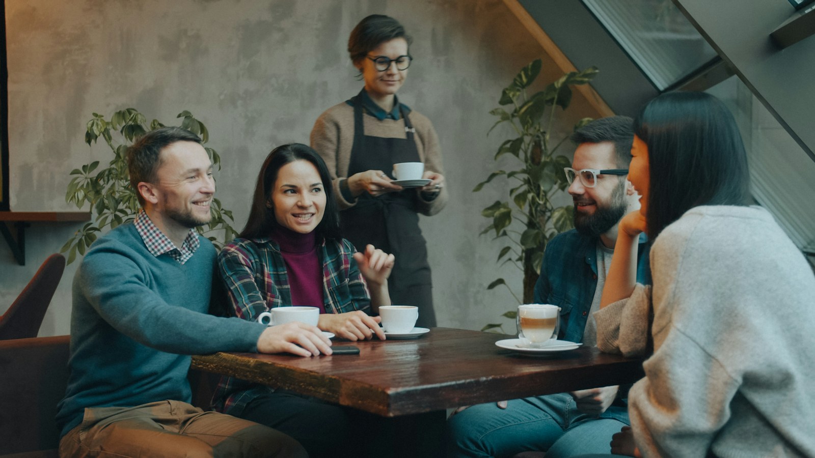 Personas conversan alrededor de una mesa en un café.
