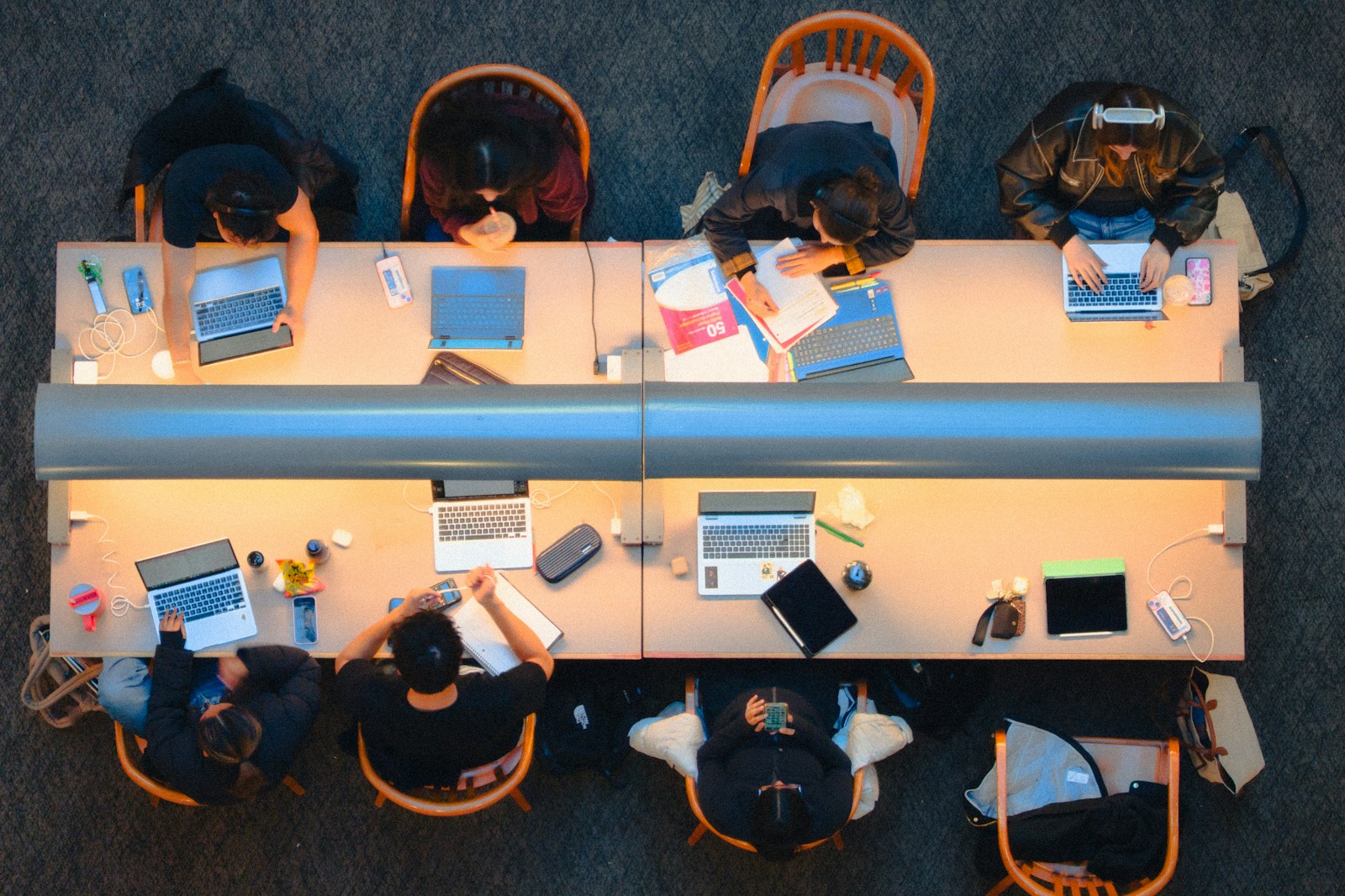 Personas estudian y trabajan juntas en una mesa larga.